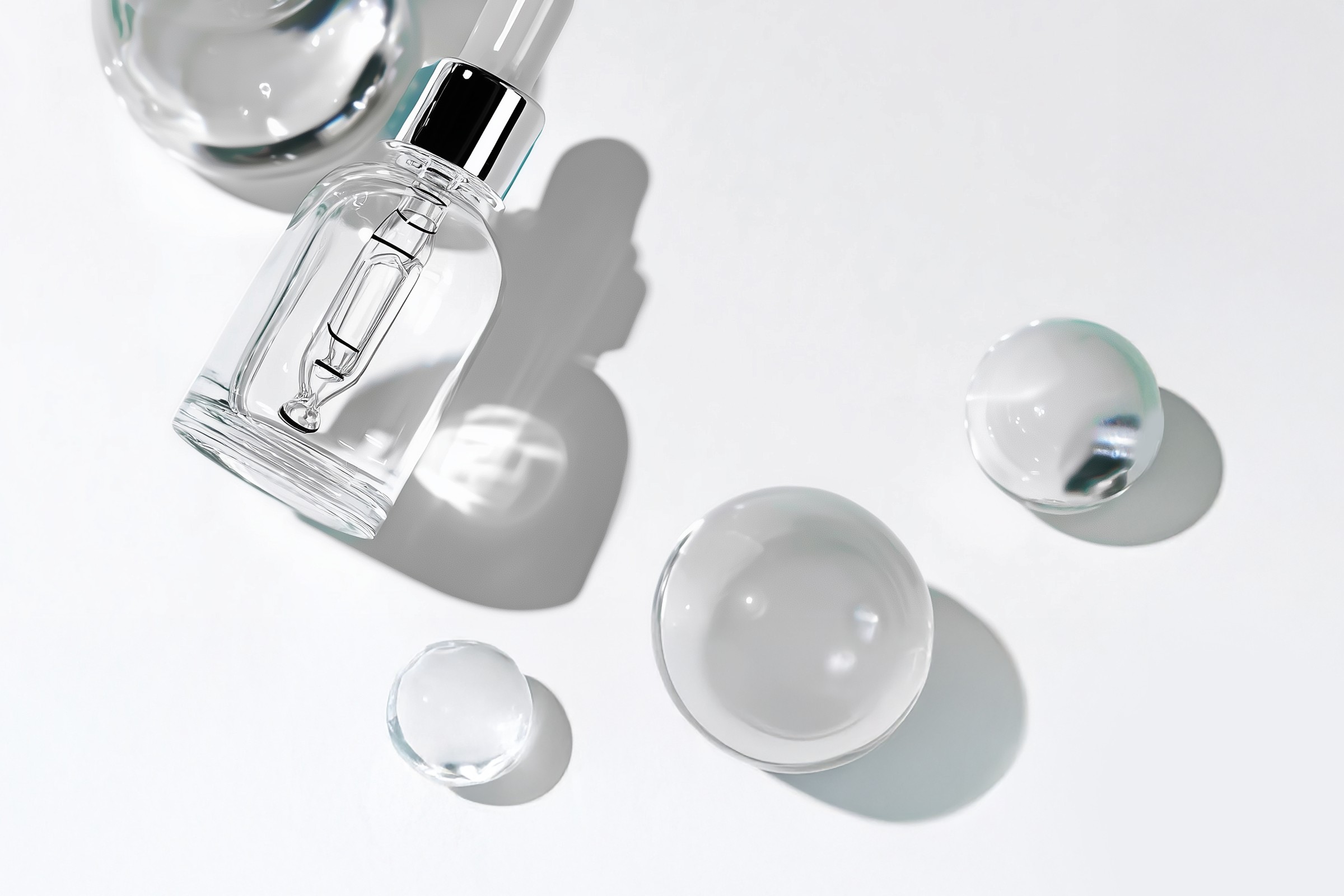 Glass dropper bottle and spheres on white lab surface